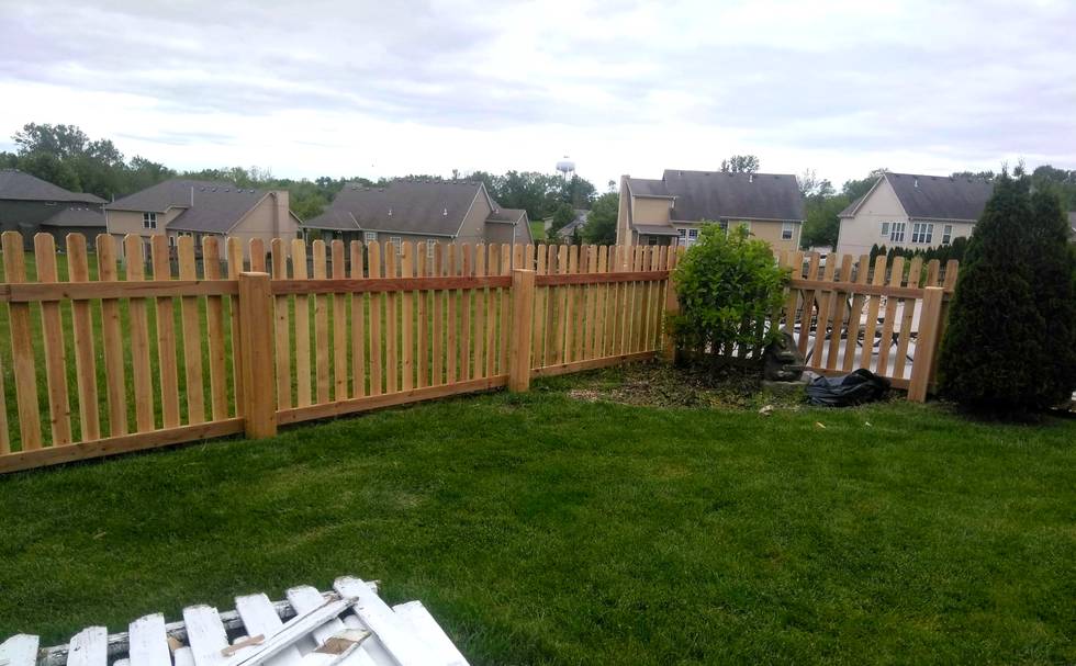 A picket fence turning a shallow angled corner across a back yard instead of a hard square corner.